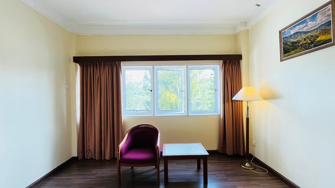 A room with a window, a chair, a table, and a lamp.