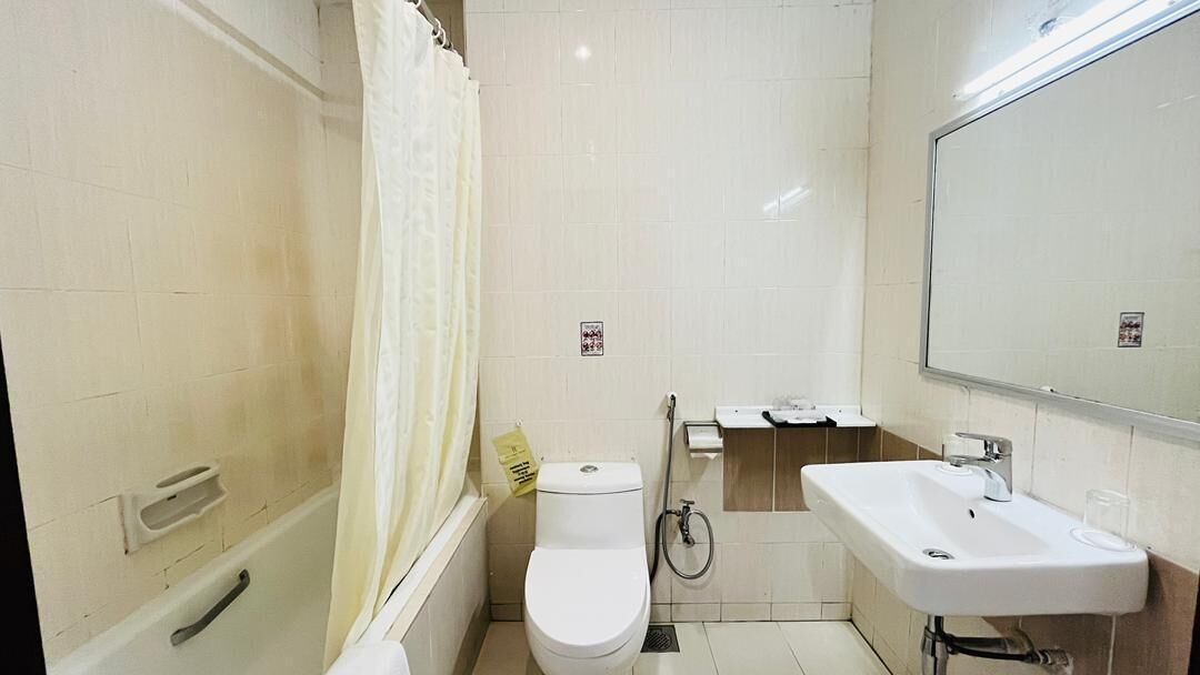 A bathroom with a toilet, shower, and sink.