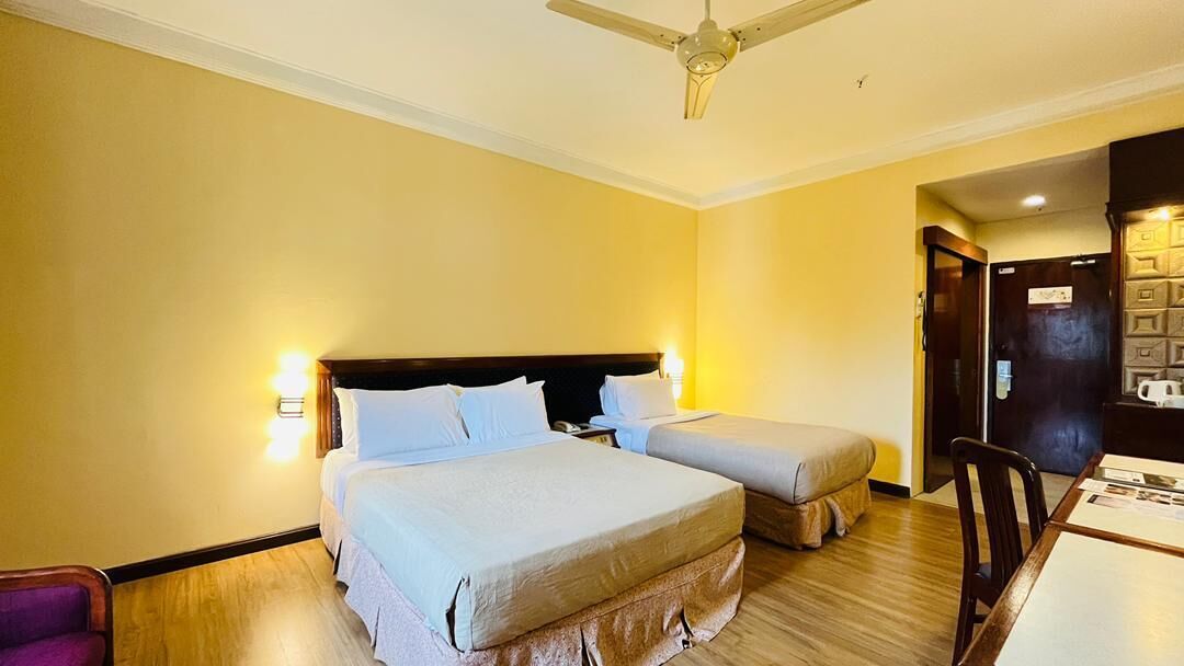 Ein Hotelzimmer mit zwei Betten, einem Esstisch und einem Deckenventilator.
