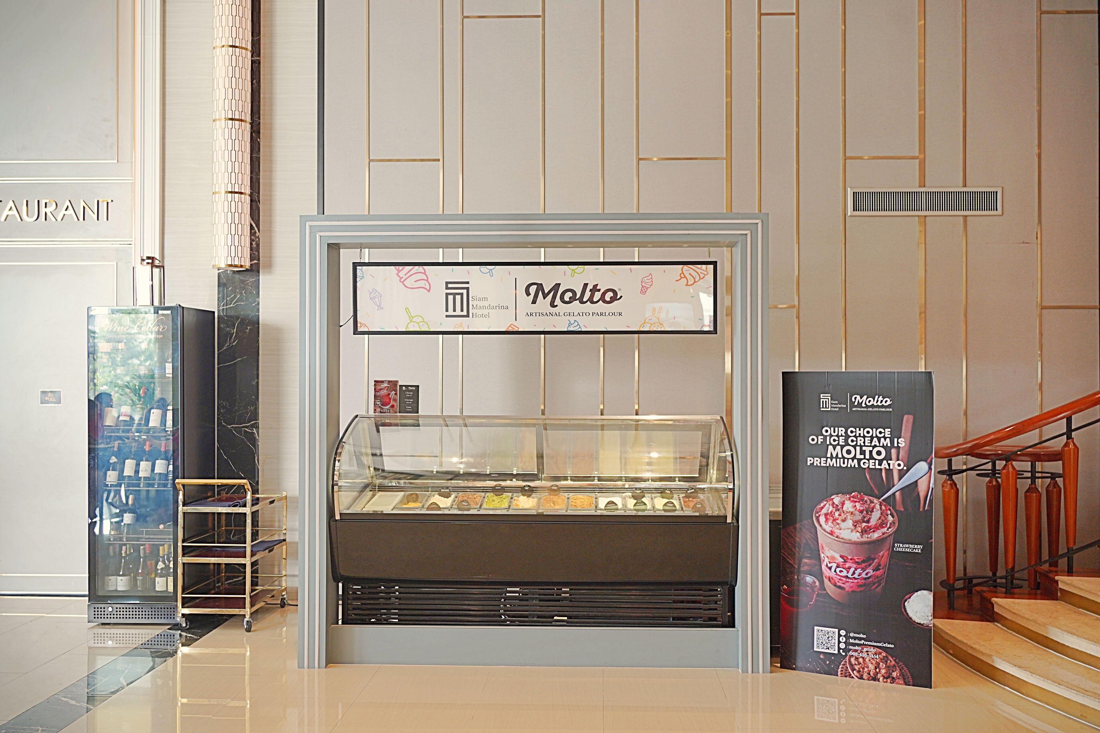 A Molto gelato display in a hotel lobby with a clear case, a signboard, and a promotional poster.