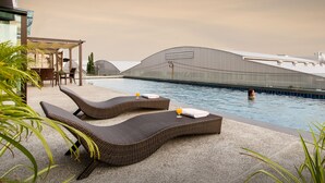Un área de piscina en la azotea con dos sillones, una mesa y una zona de estar cubierta.