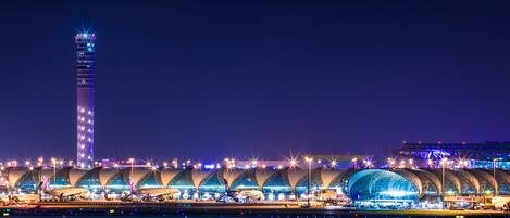 A modern airport terminal with multiple curved roofs and a tall tower.