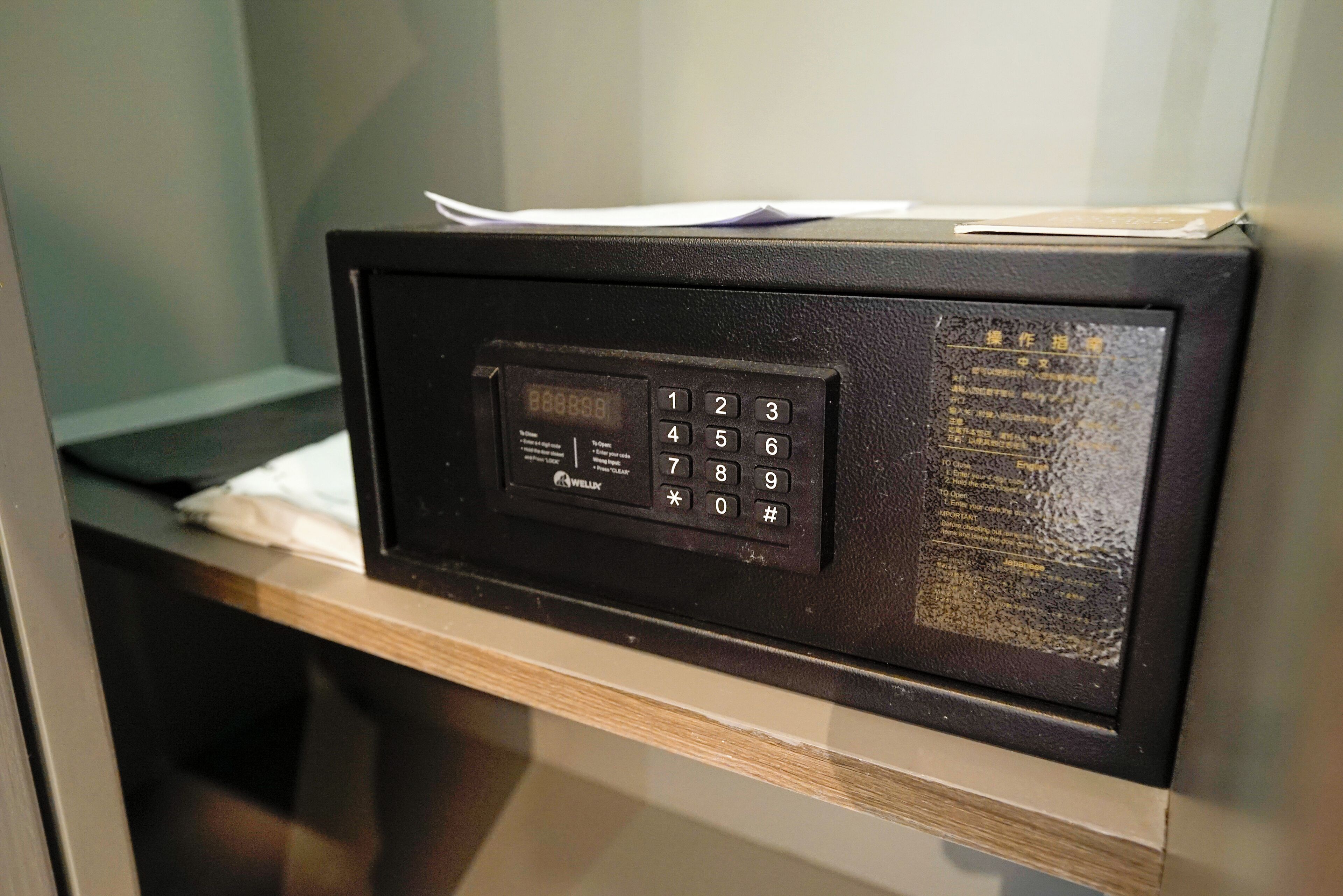 A black security keypad on a wooden counter with a paper on top.