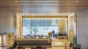 Un moderno vestíbulo de hotel con zona de estar, mostrador de recepción y vistas al exterior.