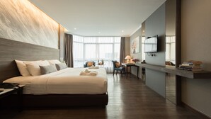 Una habitación de hotel moderna con una cama grande, un escritorio, una silla y un televisor.