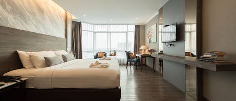 A modern hotel room with a large bed, a desk, a chair, and a TV.