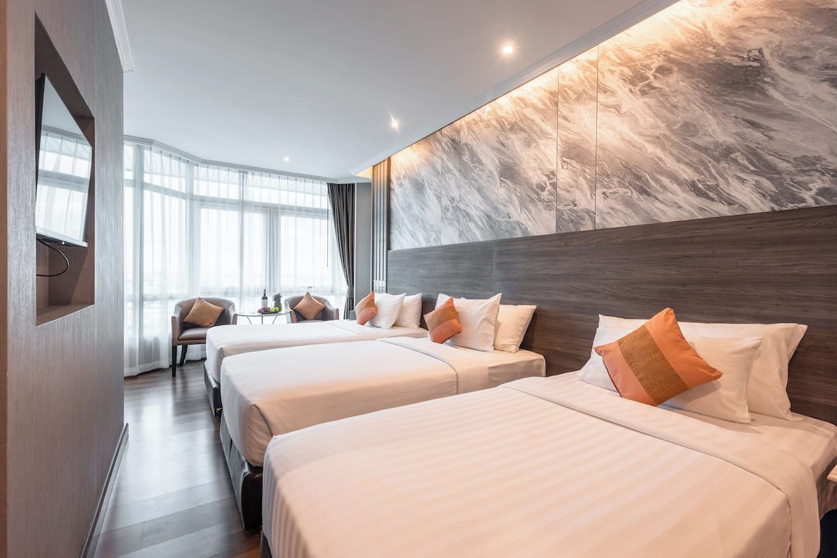 A hotel room with two beds, a large window, and a marble wall.