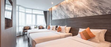 A hotel room with two beds, a large window, and a marble wall.