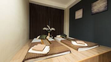 A room with two beds, a dark wall, and a wooden floor.