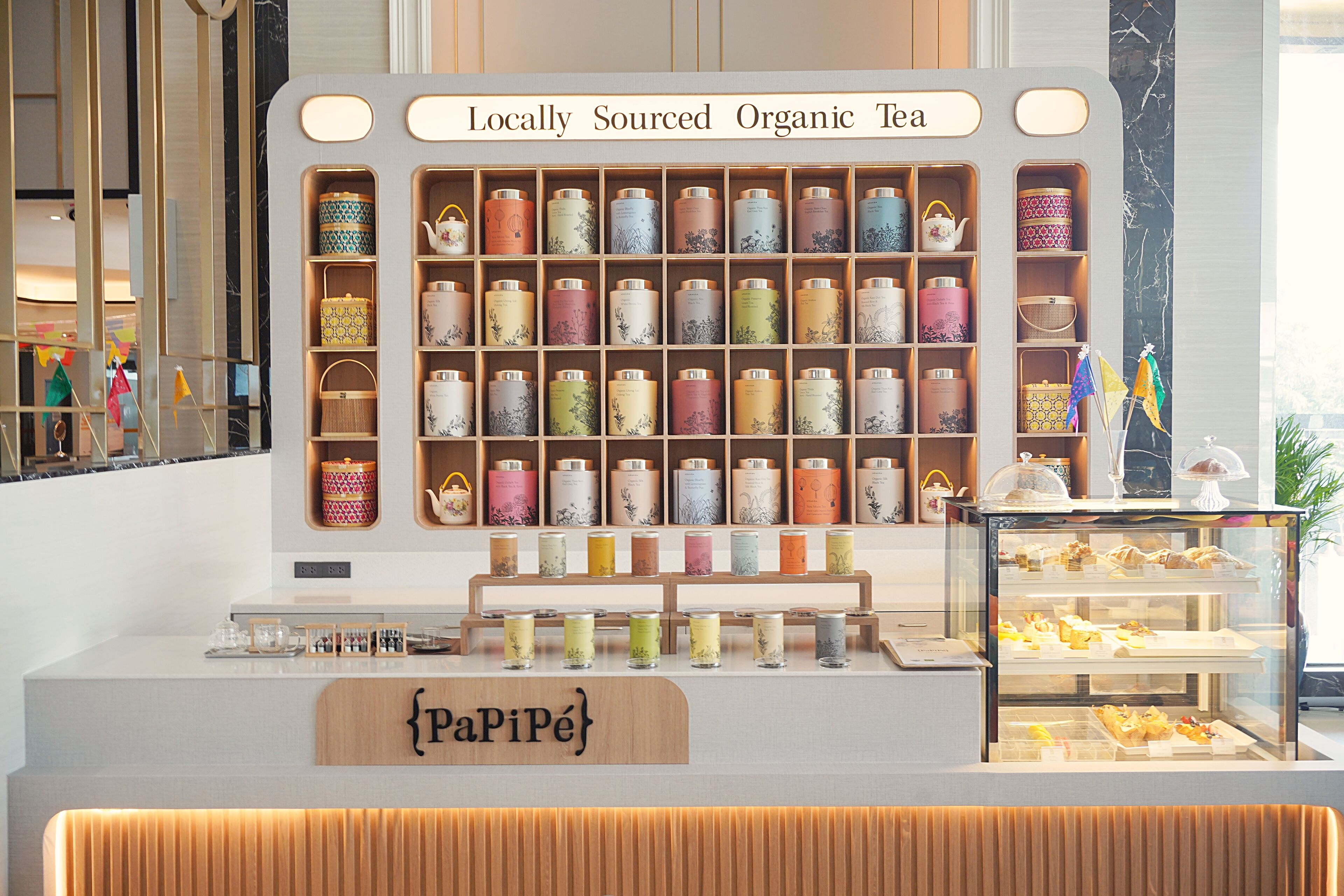 A tea shop with shelves of locally sourced organic tea and a display case with pastries.