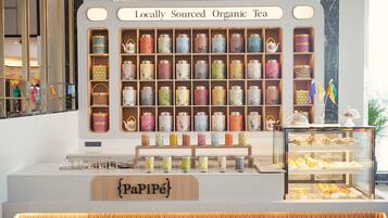 A tea shop with shelves of locally sourced organic tea and a display case with pastries.