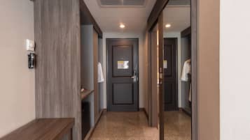 A hallway with a dark door, a coat rack, and a small shelf with a coffee maker.