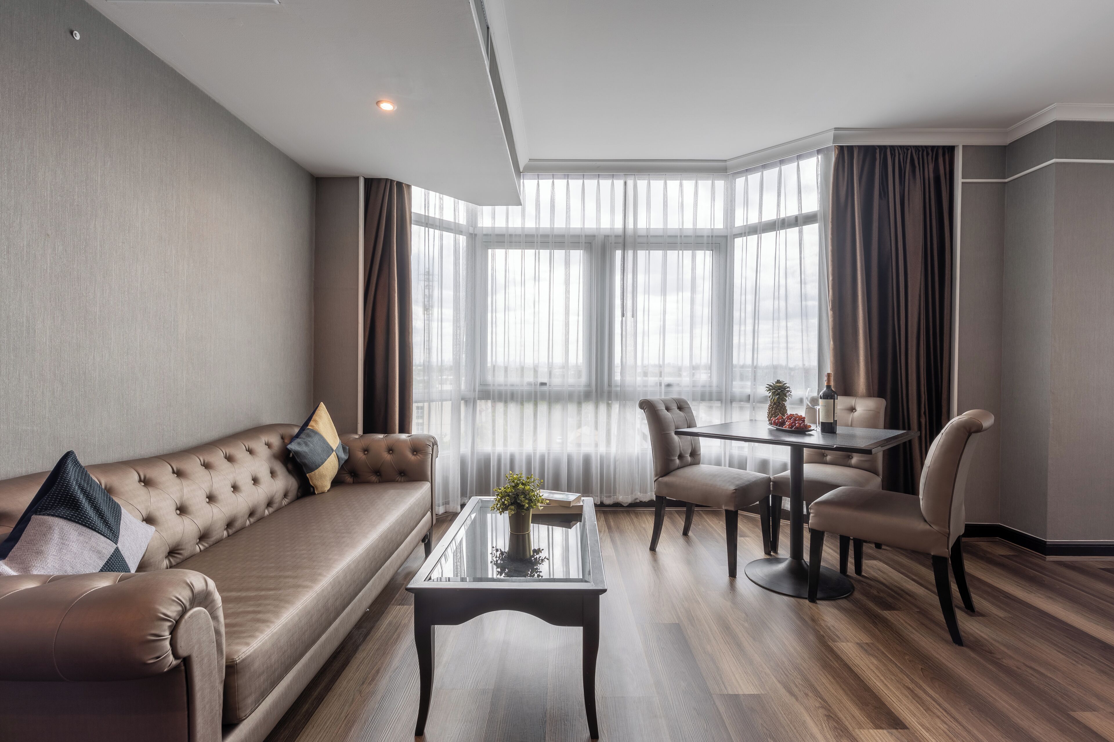 A modern living room with a sofa, a glass coffee table, and a dining area with chairs and a table.