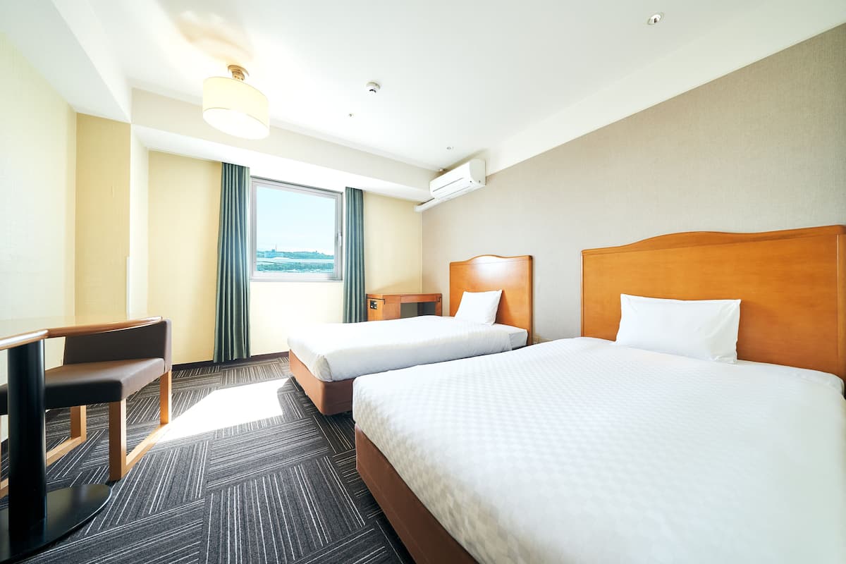Une chambre d’hôtel avec deux lits, un bureau et une chaise.