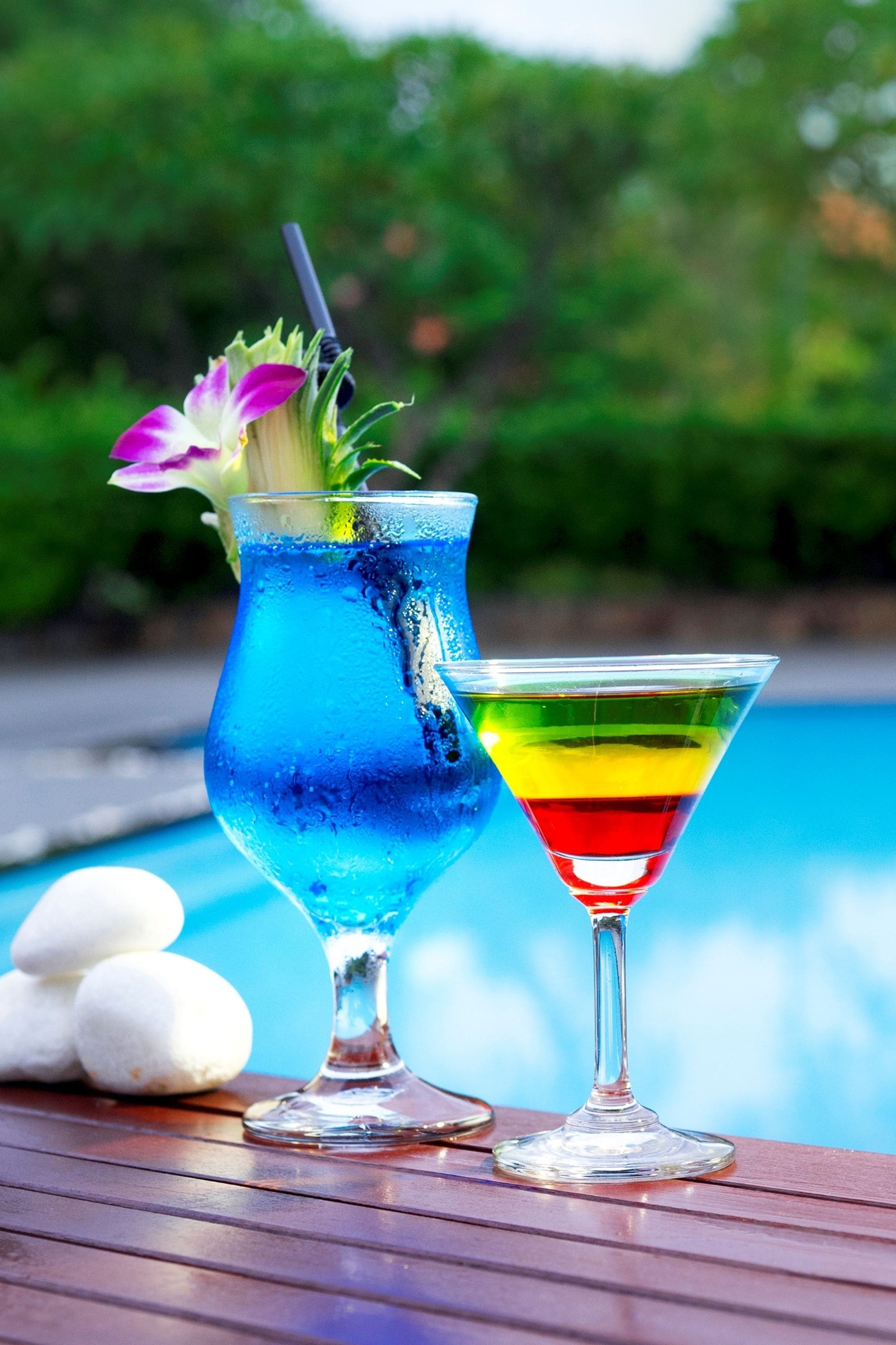 Deux cocktails sur une table en bois, près d’une piscine.
