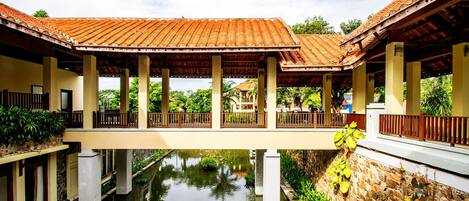 A covered walkway with columns, a water feature, and a statue.
