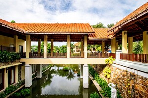 Un paseo techado con columnas, una fuente de agua y una estatua.