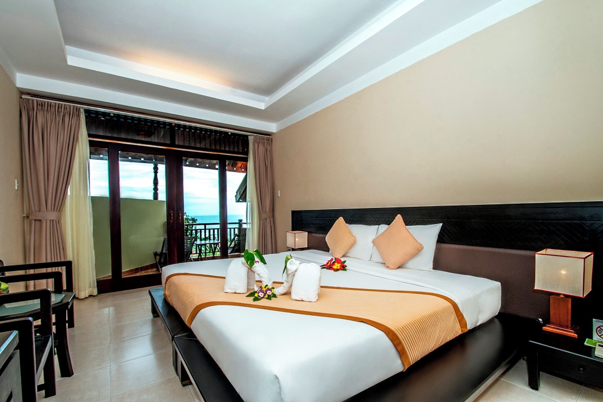 Een hotelkamer met een groot bed, een bureau, een stoel en een balkon met uitzicht.