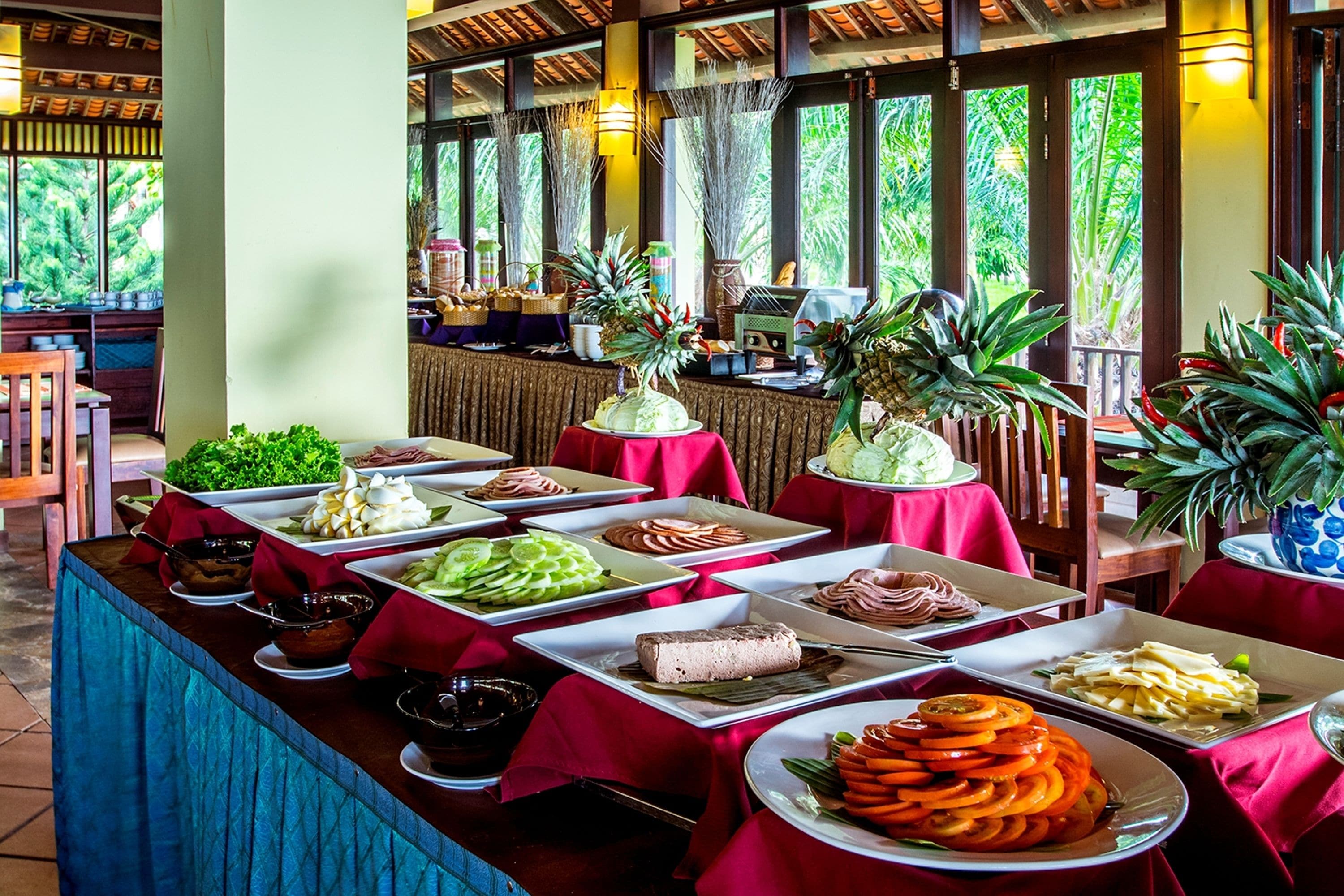 A buffet with various food items and tropical plants.