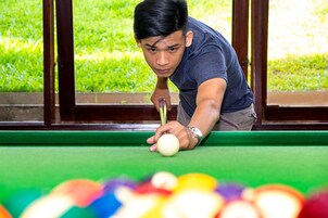 A person playing pool at a table with a green felt surface.