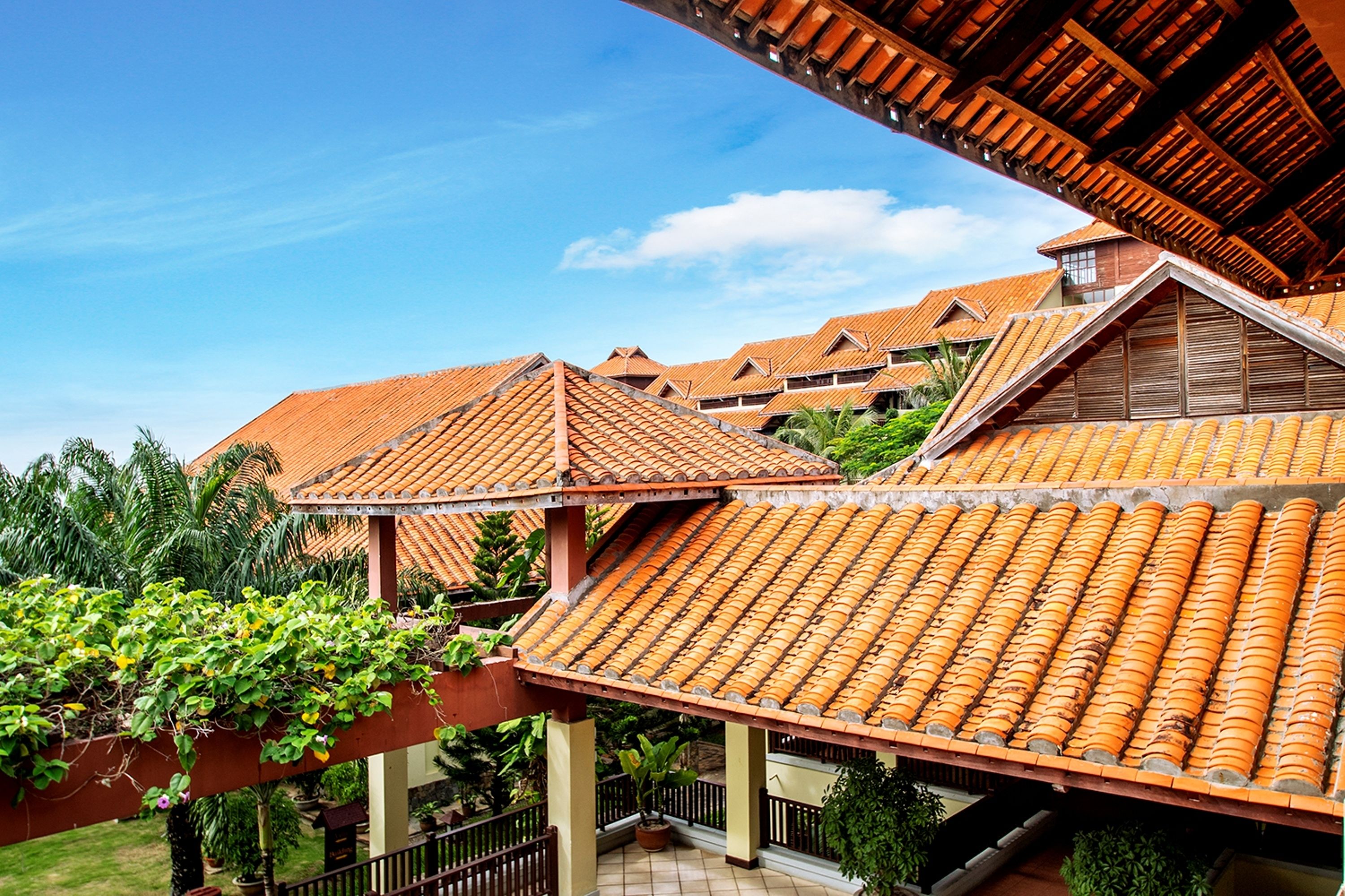 A hotel with multiple buildings, each featuring terracotta tiled roofs and a central courtyard with potted plants.