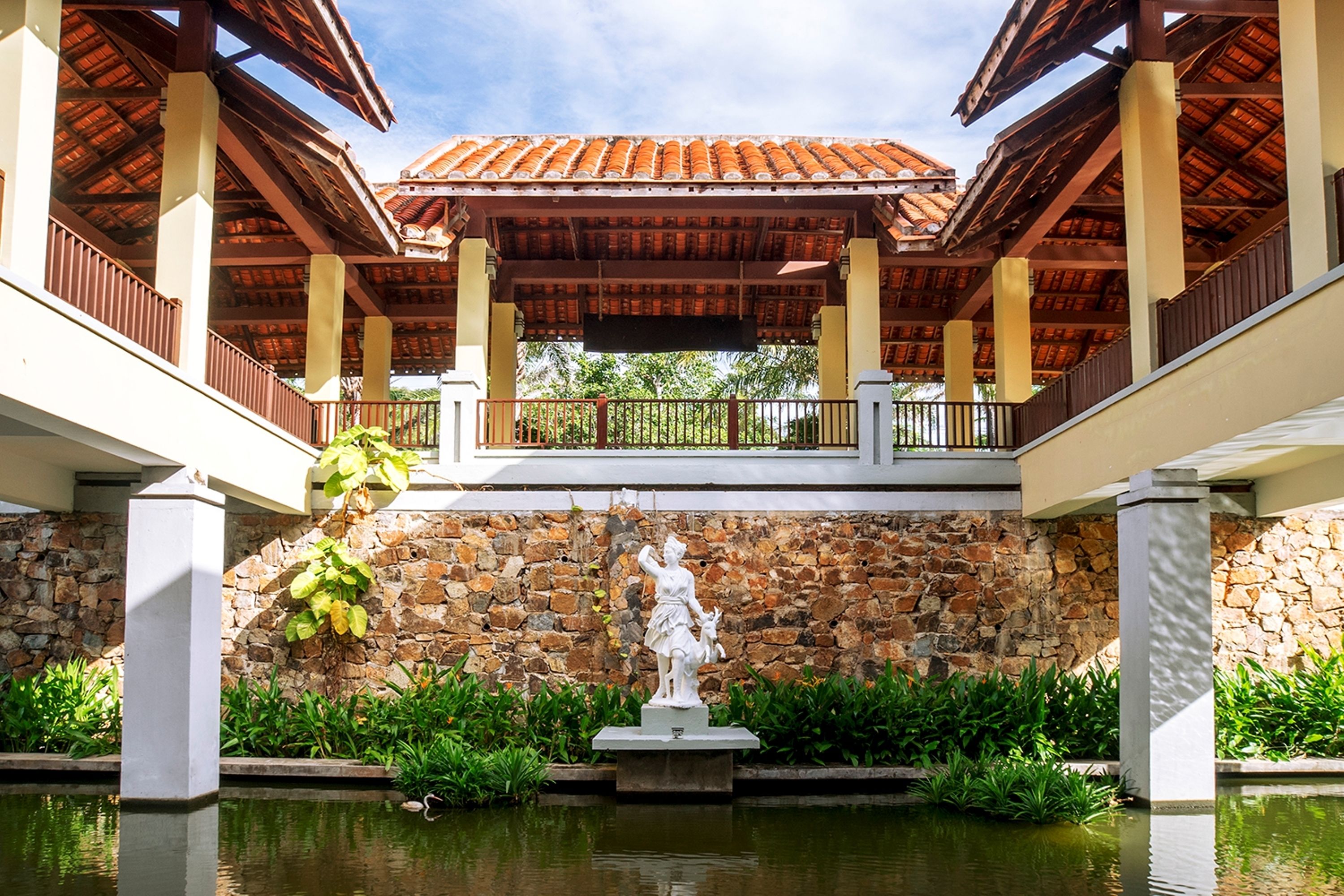 A covered outdoor area with a stone wall, a statue, and a water feature.
