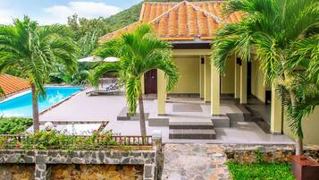 A resort with a swimming pool, palm trees, and a building with a tiled roof.