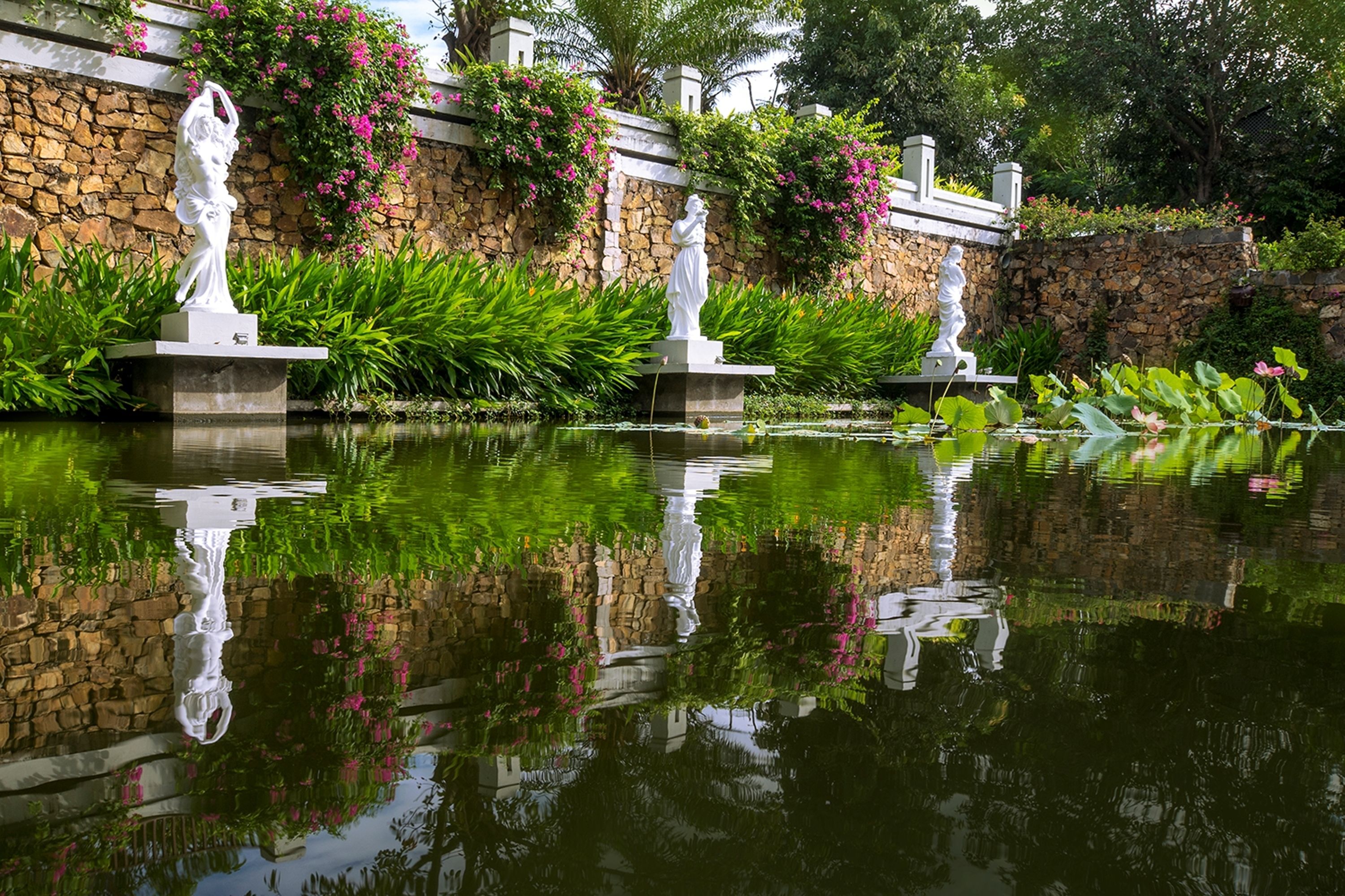 A serene garden with statues and a pond.