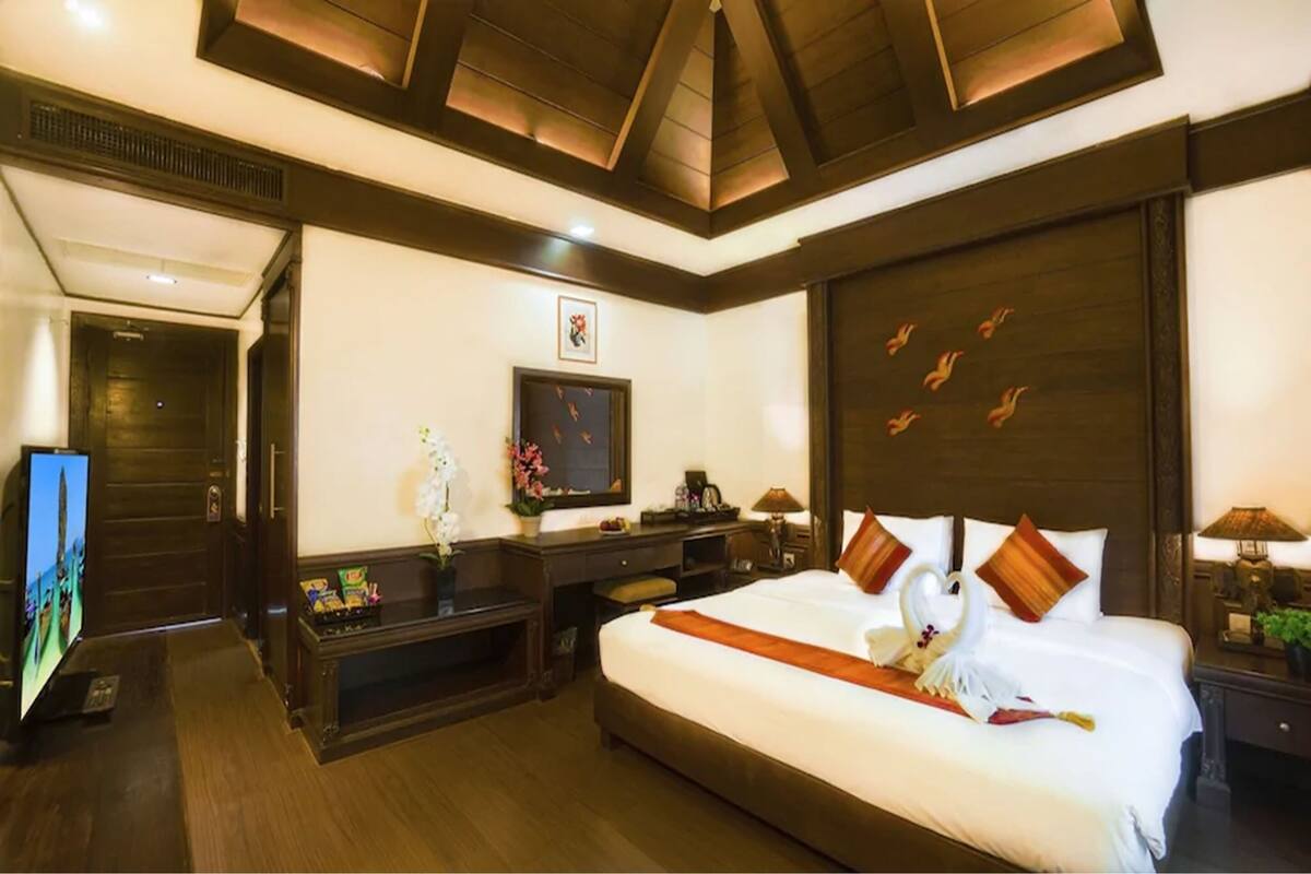 Een hotelkamer met een groot bed, een flatscreen televisie, een bureau met een computer en een televisie aan de muur.