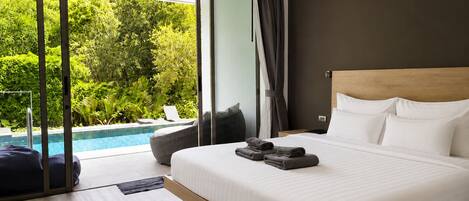 A modern hotel room with a large bed, a view of a swimming pool, and a balcony with a view of lush greenery.