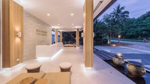 Un vestíbulo moderno con una recepción, zona de estar y vistas al exterior.
