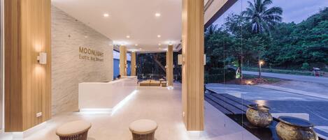 A modern lobby with a reception desk, seating area, and a view of the outdoors.