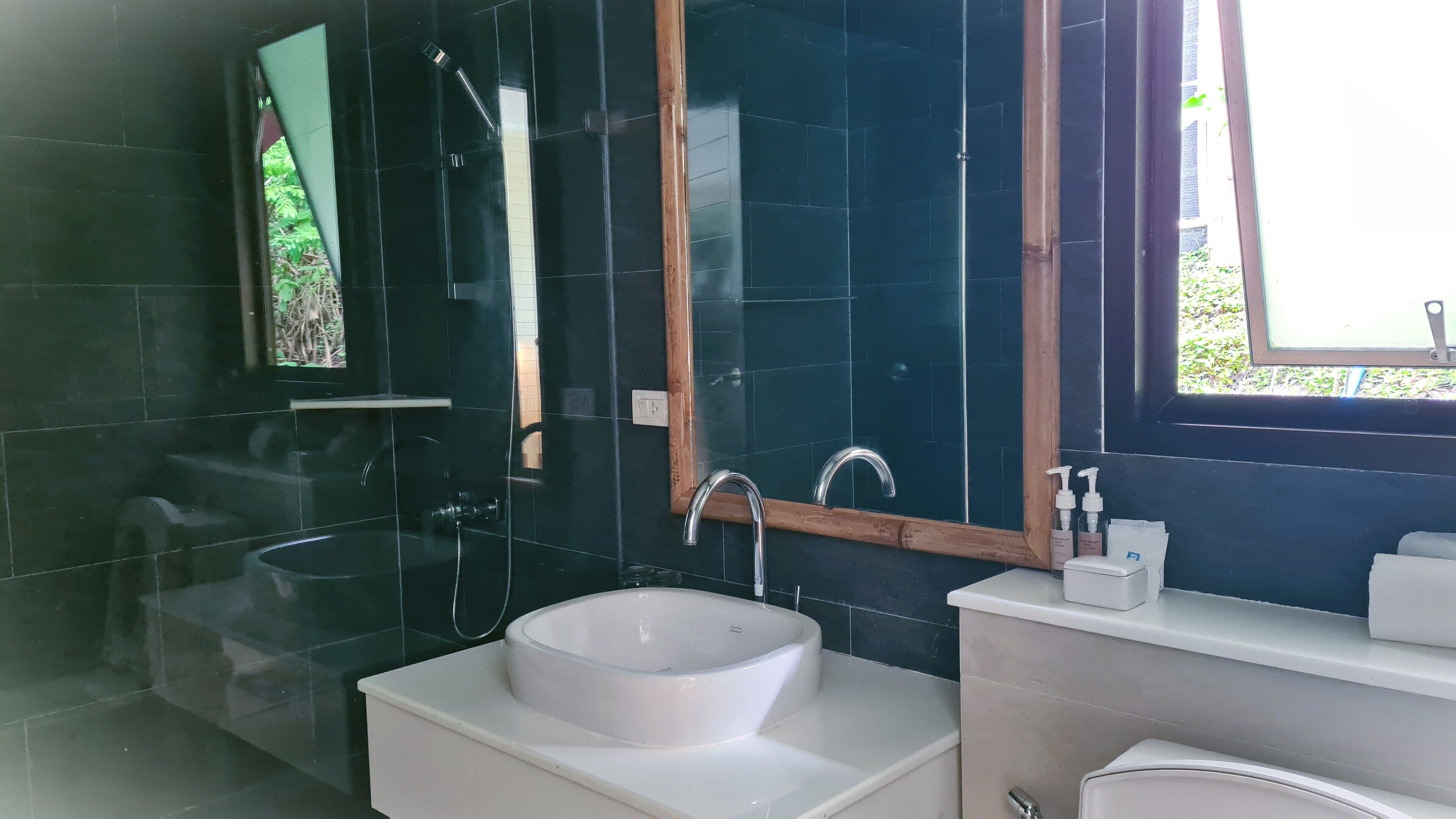 Een moderne badkamer met een witte wastafel, een spiegel en een douche.
