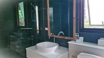 Een moderne badkamer met een witte wastafel, een spiegel en een douche.