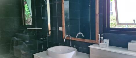 Un baño moderno con lavamanos blanco, un espejo y ducha.