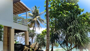 Un edificio moderno con balcón, rodeado de exuberante vegetación y palmeras.