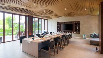 Un espace repas moderne avec une longue table, des chaises et un grand écran de télévision.