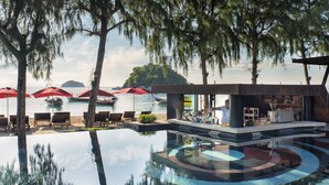 A poolside area with lounge chairs, umbrellas, and a bar.