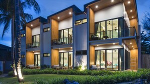 A modern multi-story building with large windows, balconies, and a well-lit exterior.