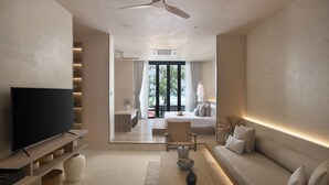 A modern living room with a flat-screen TV, a sofa, a coffee table, and a dining area. - Idyllic Concept Resort (Koh Lipe)