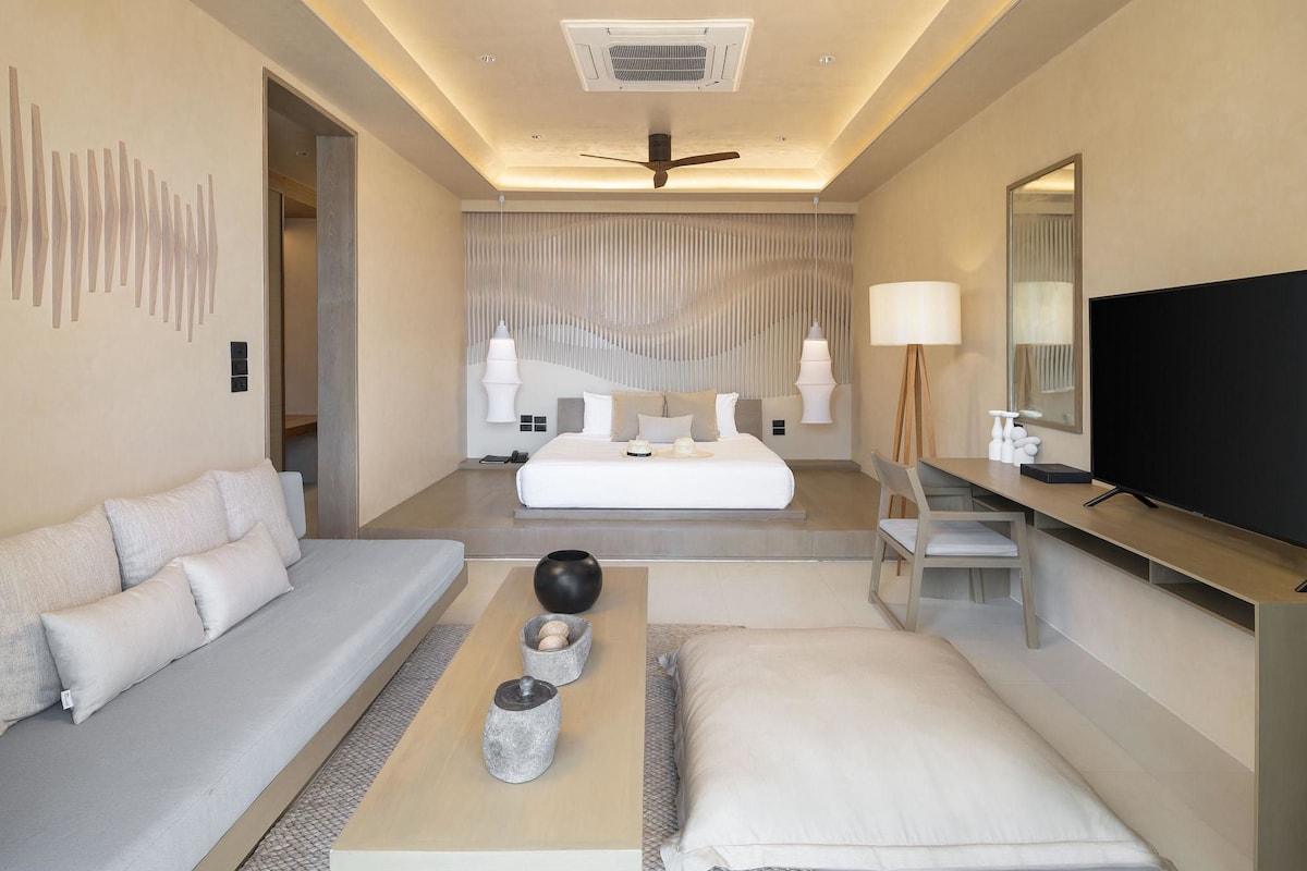 Une chambre d’hôtel moderne équipée d’un canapé, d’un lit, d’une table basse et d’un téléviseur.