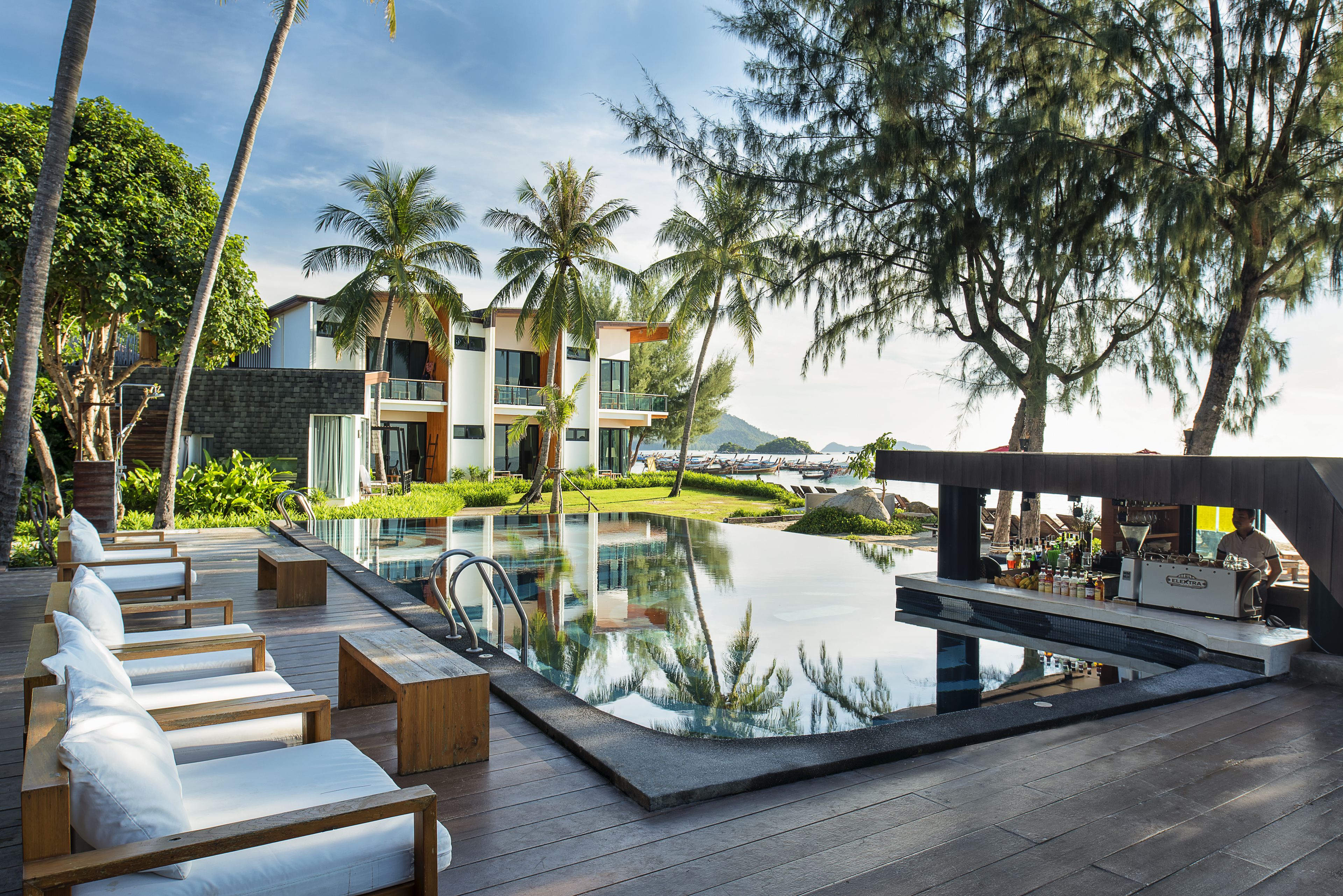 A modern resort with a pool, lounge chairs, and a bar area.