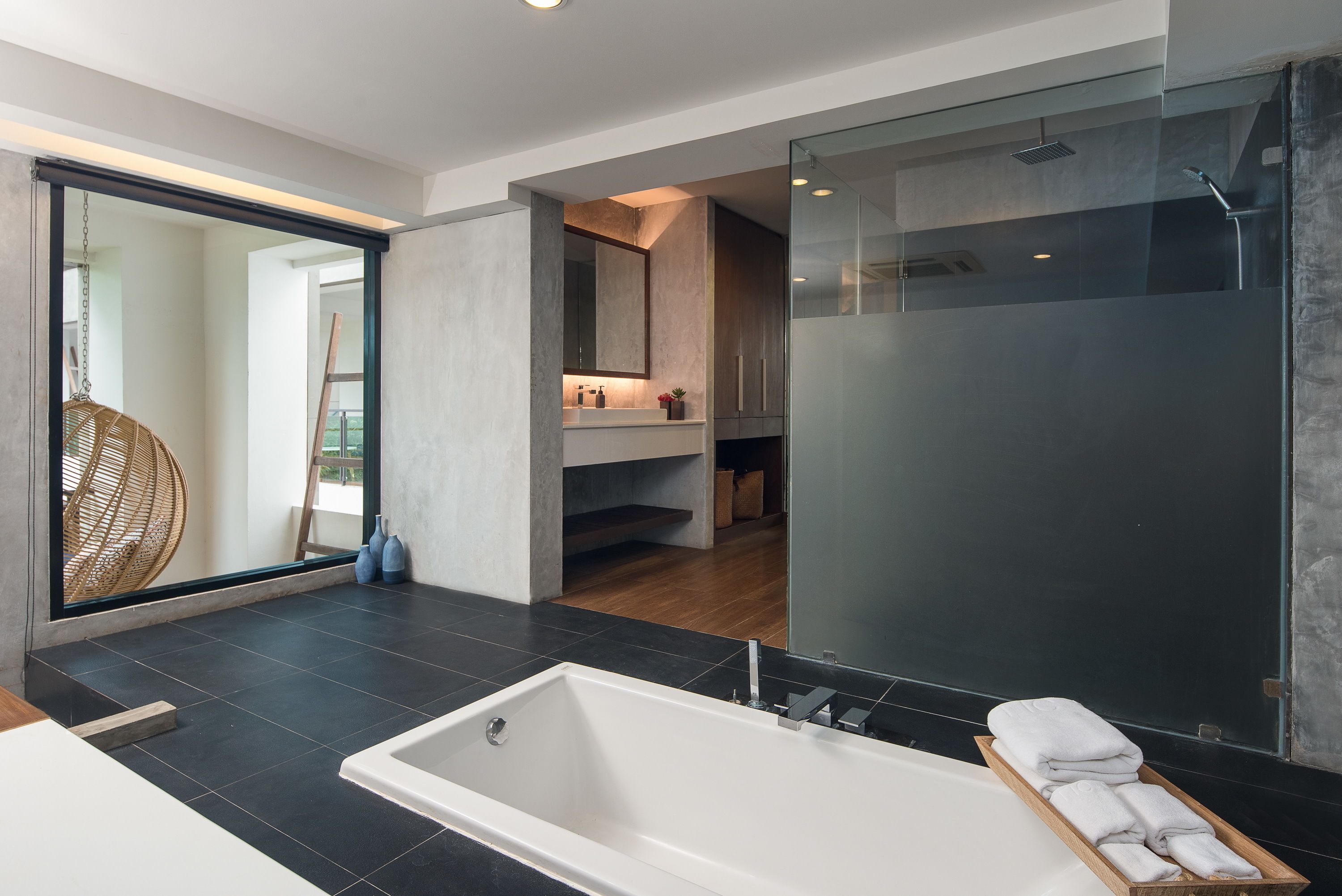 Un baño moderno con una bañera grande, cabina de ducha con paredes de vidrio y un lavamanos con espejo a la vista.