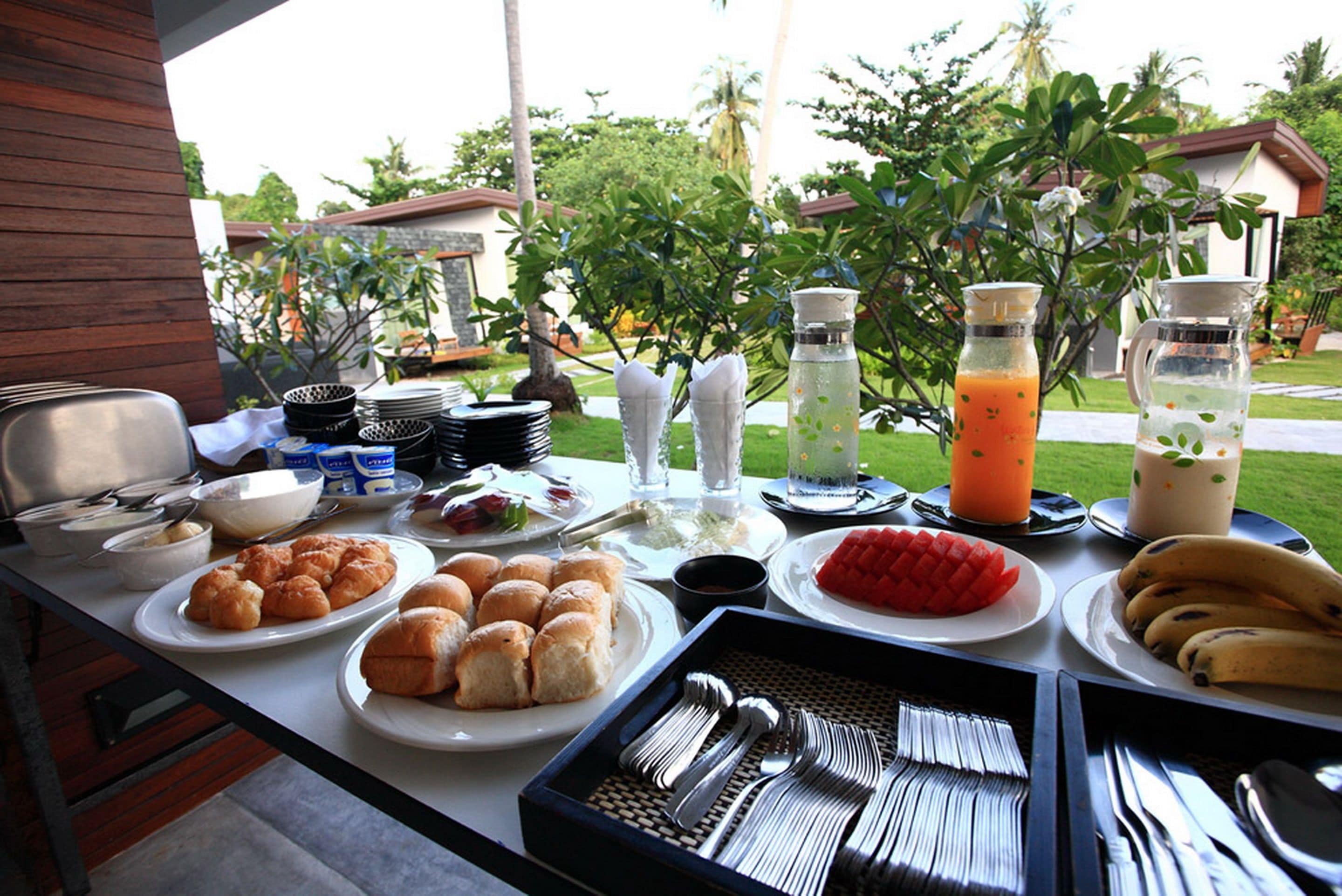 A breakfast buffet with various food items and utensils laid out on a table.