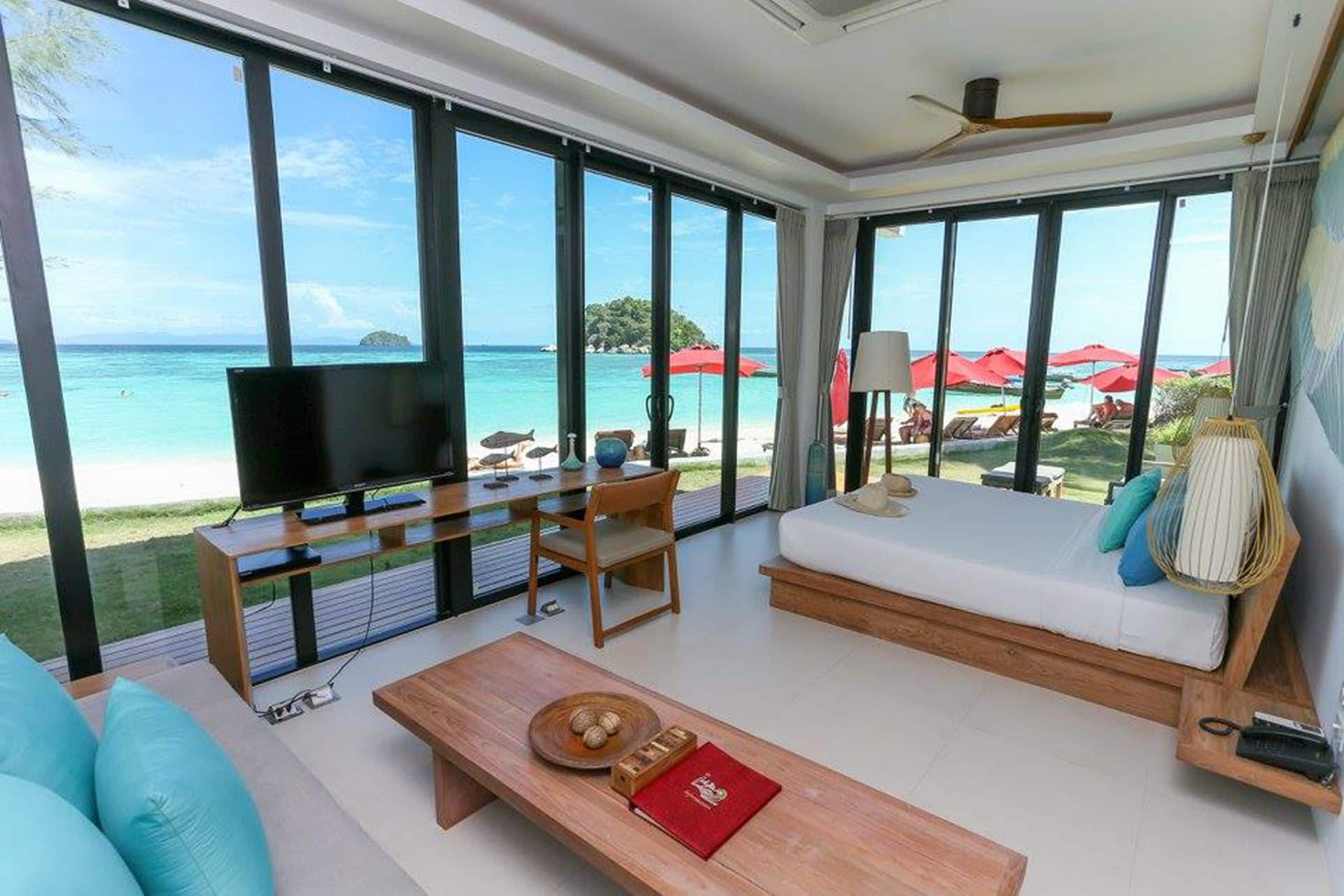 A spacious living area with a large TV, comfortable seating, and a view of the beach.