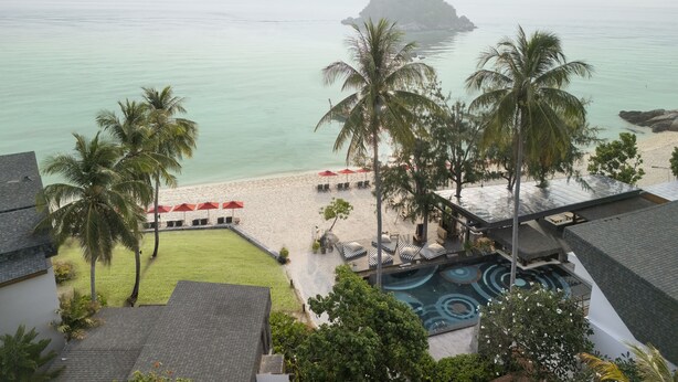 A resort with a swimming pool, beach, and palm trees.