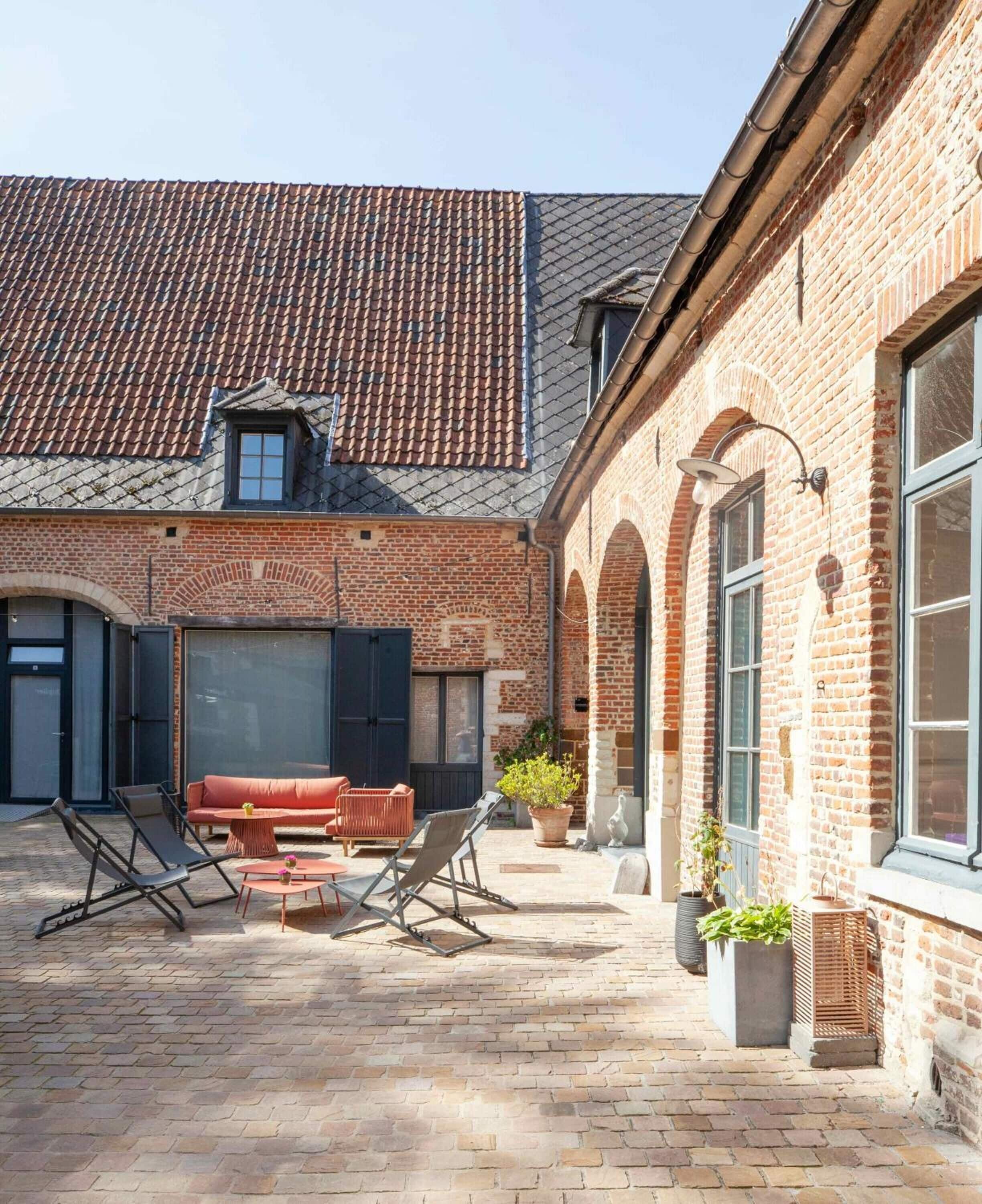 A courtyard with brick walls, a tiled roof, and outdoor seating.