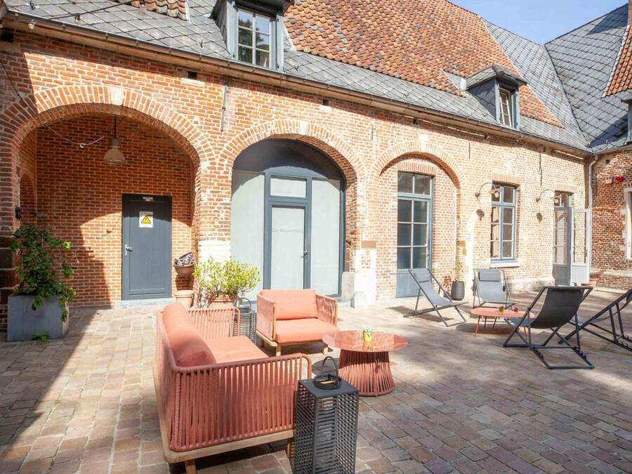 A courtyard with brick walls, arched doorways, and outdoor seating.