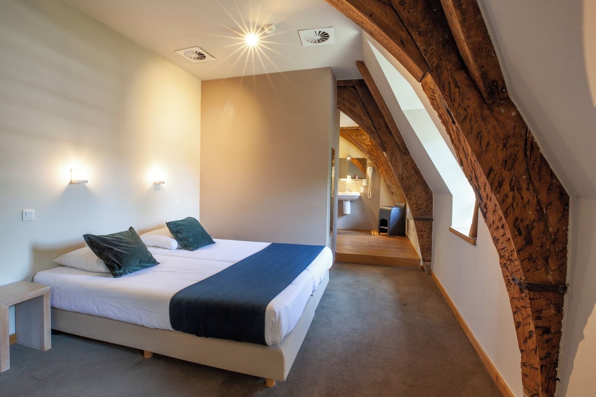 A bedroom with a large bed, a nightstand, and a wooden ceiling.
