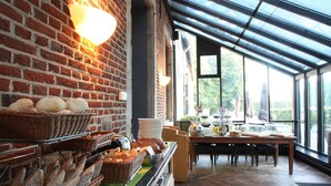 A breakfast buffet with bread, pastries, and fruits in a room with brick walls and large windows. - Hotel The Lodge Heverlee (Leuven)